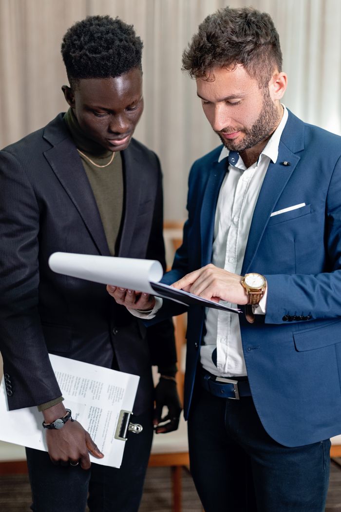 team-02 Two business professionals in corporate attire reviewing documents indoors.